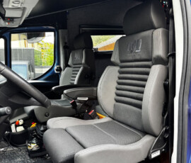 Interior of a truck cab showing the driver and passenger seats, steering wheel, and dash area.